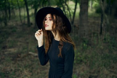 Siyah şapkalı kadın ormanda fantezi kuruyor.