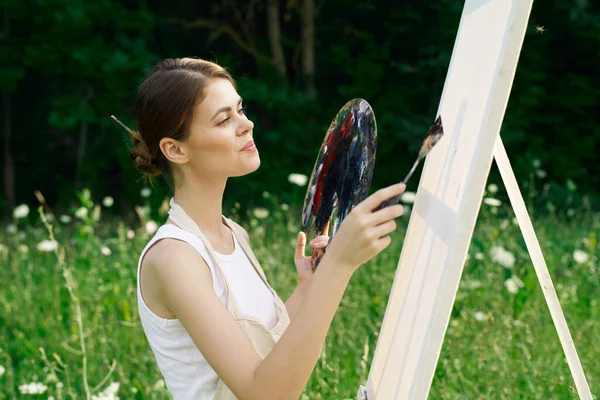 Cheerful woman paints a picture palette nature landscape — Stock Photo, Image