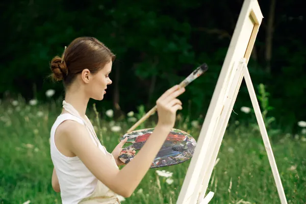 Cheerful woman artist painting a picture outdoors creative art — Stock Photo, Image