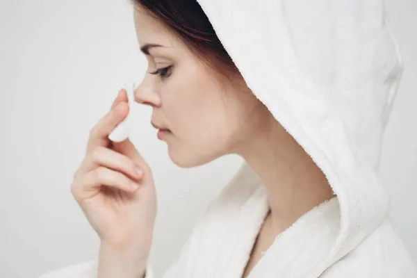 Mulher com um capuz na cabeça limpa o rosto com uma almofada de algodão cuidados com a pele — Fotografia de Stock