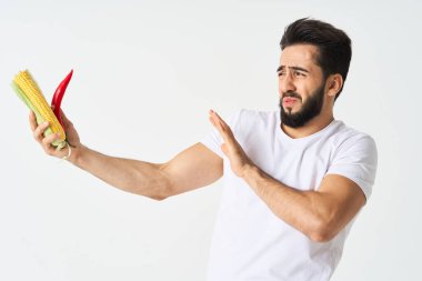 Elinde sebzelerle sakallı bir adam. Sıcak biberli mısır.