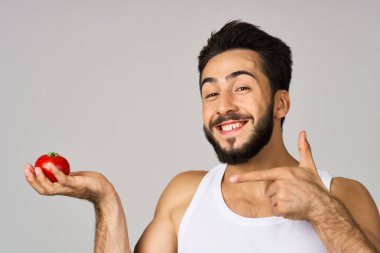 Beyaz tişörtlü bir adam. Taze domatesler. Sağlıklı yaşam tarzı.