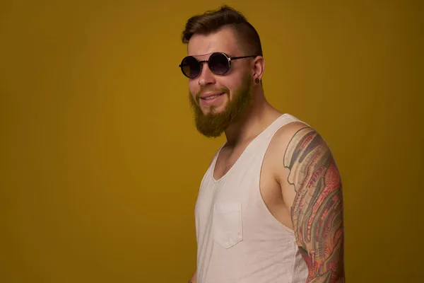 Homem em uma t-shirt branca tatuagens em seus braços moda óculos estilo moderno — Fotografia de Stock