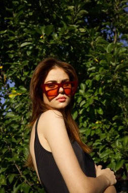 Güneş gözlüğü takan güzel kadın yeşil yapraklı yaz modeli.