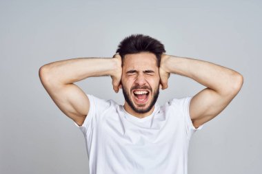 Beyaz tişörtlü sakallı adam elleriyle el kol hareketi yapıyor.