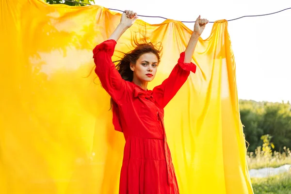 Sarı arka plan pozu veren kırmızı elbiseli çekici kadın.