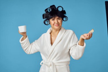 Beyaz önlüklü ev hanımı, mavi arka planı temizliyor.