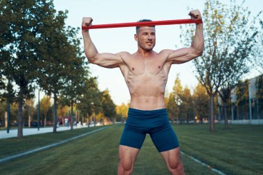 Parktaki spor salonunda mavi şortlu bir adam.