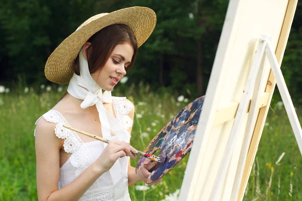 Женщина в белом платье на улице художник рисует мольберт — стоковое фото