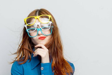 Yüzünde mavi gömlekli, göz kamaştırıcı gözlüklü bir kadın.