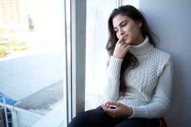 Beyaz kazaklı esmer, depresyondan dışarı bakıyor.