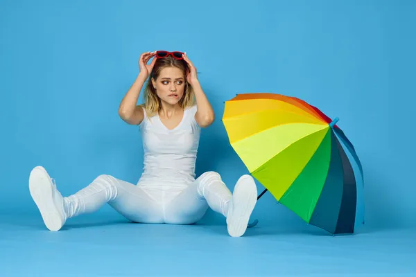 Modieuze vrouw met paraplu regenboog kleuren poseren blauwe achtergrond — Stockfoto