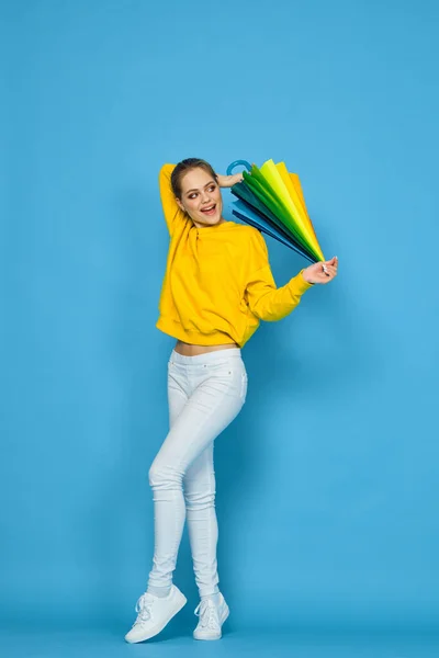 黄色のセーターに多色の傘を持つ女性が虹色をポーズ — ストック写真