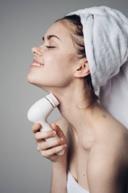 Kafasında havlu olan kadın yüz masajcısı cilt hijyeni