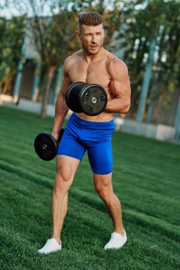 Parktaki spor egzersizinde şişirilmiş vücutlu bir sporcu.
