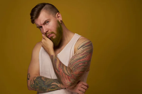 Man met baard in wit t-shirt met tatoeages op zijn armen die een serieuze look vormen — Stockfoto