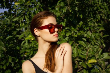 Yeşil yaprakların arkasında poz veren çekici bir kadın.