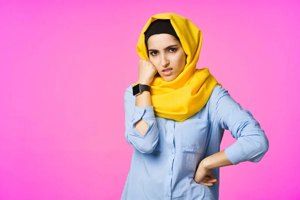 Vrolijke vrouw in gele hijab elektronische horloge technologie gebruiker roze achtergrond — Stockfoto