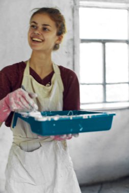 Beyaz önlüklü ev dekorasyonu yapan kadın ressam.