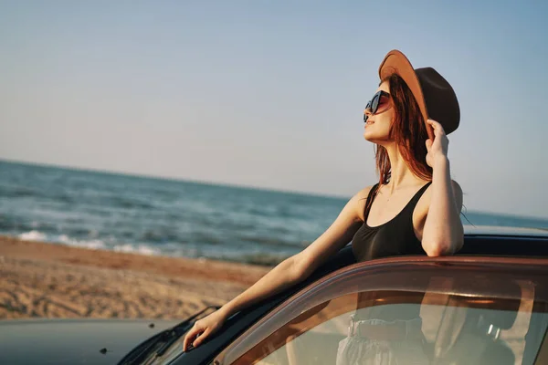 Hübsche Frau mit Sonnenbrille in der Nähe des Autos am Strand — Stockfoto