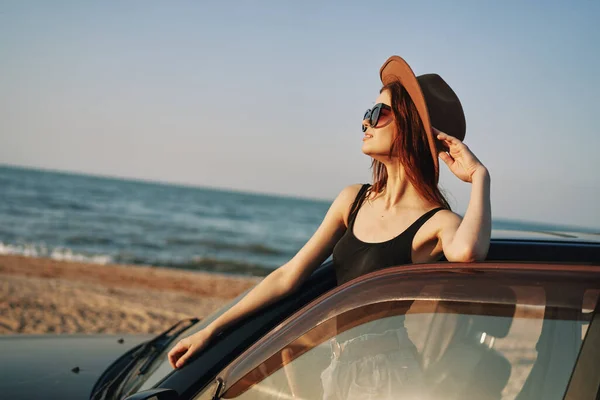 Hübsche Frau mit Sonnenbrille in der Nähe des Autos am Strand — Stockfoto