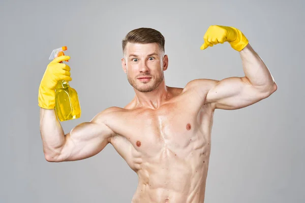 头戴黄色橡胶手套，肌肉抽吸洗涤剂清洗的男人 — 图库照片