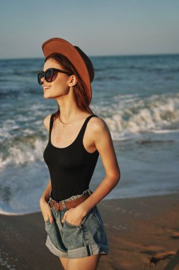 Kumsalda yürüyen bir kadın, tatil güneşinde seyahat ediyor.