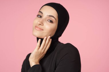 neşeli Müslüman kadın siyah tesettüre poz veren el hareketi pembe arka plan