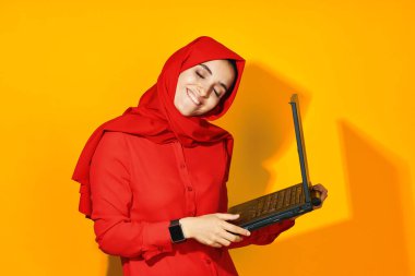 Dizüstü bilgisayarı olan neşeli bir kadın. Teknoloji duyguları sarı arka plan.