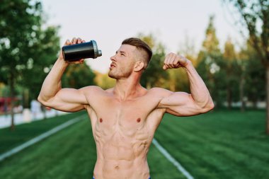 Parktaki egzersiz motivasyonunda kaslı vücutlu atletik bir adam.