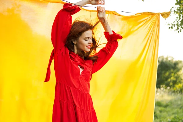 Glad kvinna i röd klänning poserar i naturen gul duk — Stockfoto