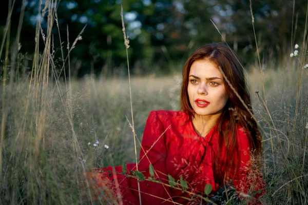 Kırmızı elbiseli kadın çimenlerin üzerinde uzanmış, doğa modasında. — Stok fotoğraf