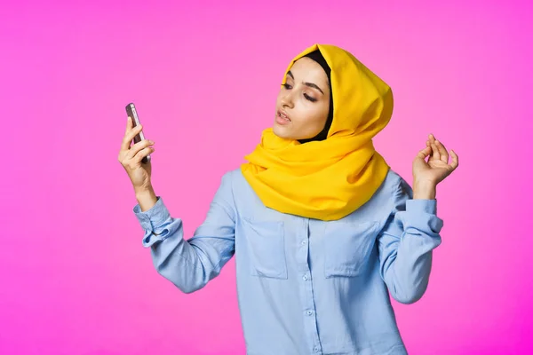 Весела жінка в жовтому хіджабі з телефоном в руках технологія комунікації — стокове фото