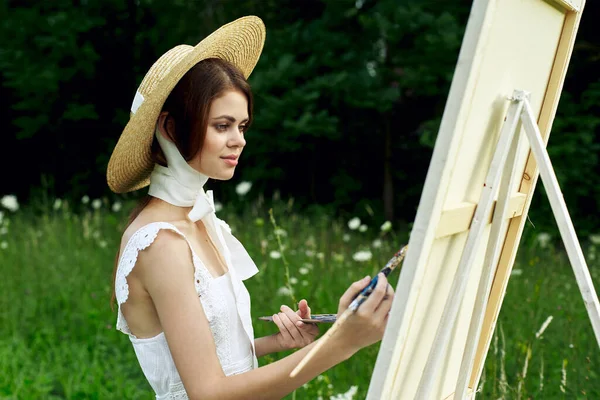 Şapkalı güzel kadın doğa boyası üzerine bir resim çiziyor. — Stok fotoğraf