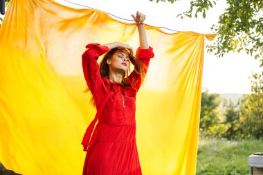 Kırmızı elbiseli neşeli bir kadın elleriyle işaret ediyor.