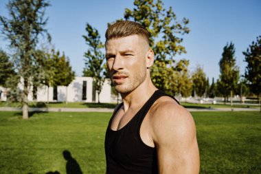 Siyah tişörtlü spor adam parkta yaşam tarzını eğitiyor.