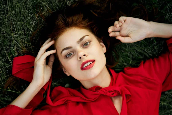 Mulher em vestido vermelho encontra-se na grama endereço moda verão — Fotografia de Stock