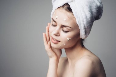 Çıplak omuzlu kadın yüz kremi sürmüş.