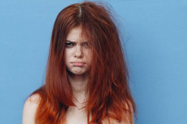 Güzel bir kadın yaramaz saçlarını mavi arka planda tarıyor