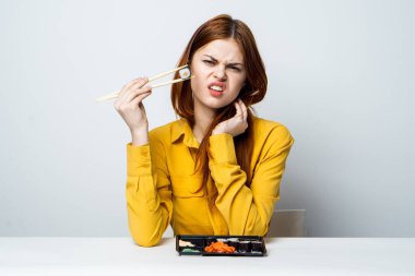Masada suşi yiyen bir kadın Japon atıştırmalığı yiyor.