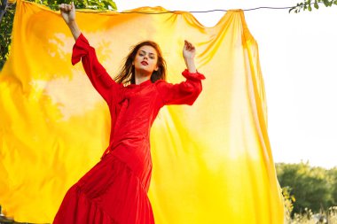 Güzel bir kadın kırmızı elbiseli, açık havada sarı kumaşlı.