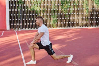 Atletik erkekler yazın spor sahasında egzersiz yapıyorlar.