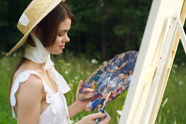 帽子アーティストのかなりの女性が自然の絵を描いています — ストック写真