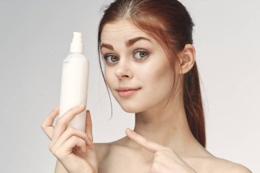 Çıplak omuzlu bir kadın cilt bakım kremi kullanıyor.