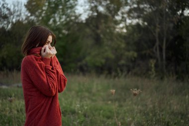 Dışarıda kırmızı kazaklı bir kadın var.