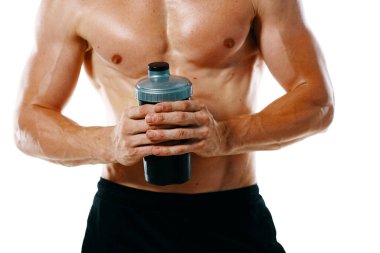 Şişirilmiş gövdesi olan atletik bir adam. Spor tükürüğü şişesi içiyor.