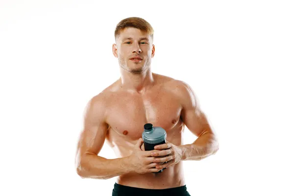 Um homem um atleta com um corpo bombeado bebe de uma garrafa — Fotografia de Stock