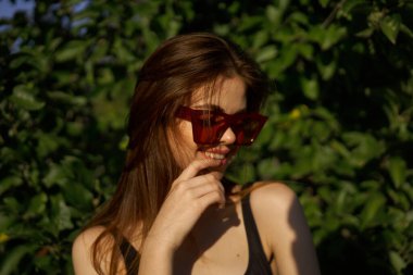 Yeşil yaprakların arkasında poz veren çekici bir kadın.