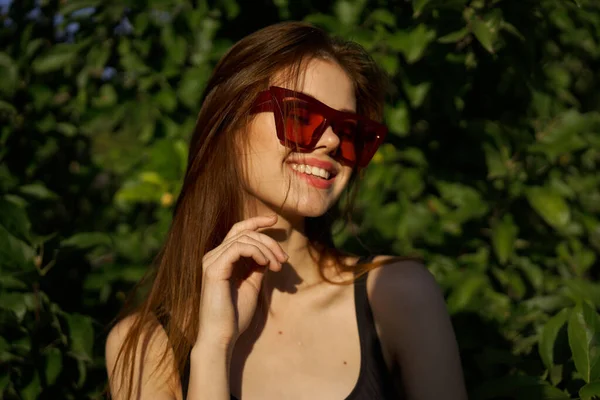 Yeşil yaprakların arkasında poz veren çekici bir kadın.