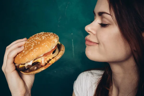 Wesoła kobieta z hamburgerem w pobliżu twarzy przekąski fast food — Zdjęcie stockowe